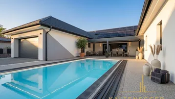 Moderner Außenbereich mit großem Pool, Garage und sonniger Terrasse am Haus.