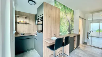 Moderne Küche mit integrierten Geräten, Frühstücksbar und einer auffälligen Natur-Wandtapete.