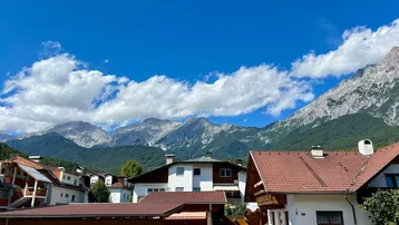Panoramablick auf eine Wohnsiedlung mit traditionellen Häusern vor einer beeindruckenden Bergkulisse.