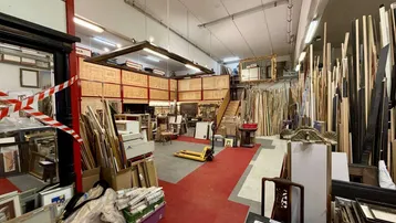 Großer, offener Werkstatt- und Lagerbereich mit hohen Decken und vielen Materialien für die Rahmenherstellung.