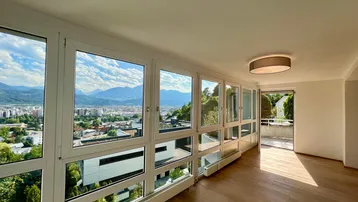 Heller Wohnbereich mit großen Fenstern, die einen weiten Blick auf die Stadt und die Berge bieten.