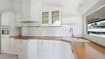 Klassische weiße Küche mit Holz-Arbeitsplatten, Fliesenrückwand und Fenster.