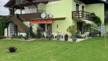 Weitläufiger Garten mit Rasenfläche und Blick auf die Rückseite des Hauses mit Balkonen und Terrassen.