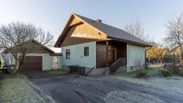 Einfamilienhaus mit Satteldach, angrenzender Garage und gepflasterter Auffahrt im winterlichen Ambiente.