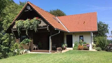Charmantes Haus mit Holzelementen, rotem Ziegeldach und einer überdachten Veranda im Grünen.