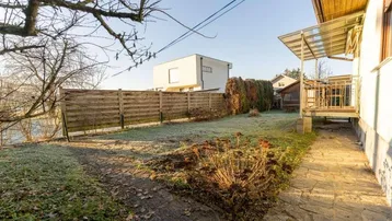Gepflegter Gartenbereich mit Rasenfläche, Holzzaun und Blick auf die umliegende Bebauung.