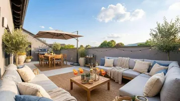 Geräumige Dachterrasse mit gemütlicher Lounge-Ecke, Essbereich und Grillstation unter blauem Himmel.