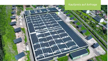 Luftaufnahme einer großen Industriehalle mit zahlreichen Photovoltaikmodulen auf dem Dach und umliegenden Freiflächen.