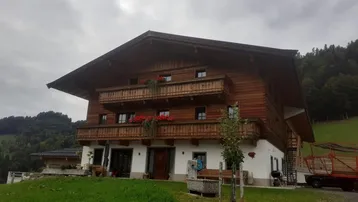 Traditionelles Holzhaus im alpinen Stil mit Balkonen und grüner Umgebung.
