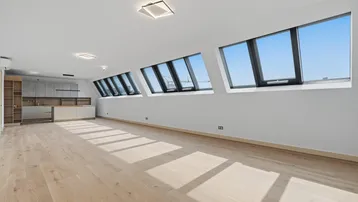 Heller, offener Wohnbereich mit Dachschrägenfenstern und integrierter Küche, ideal für modernes Wohnen.