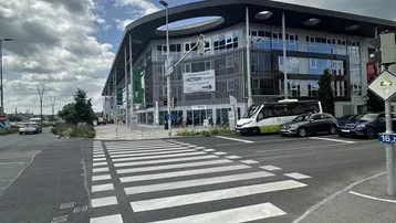 Modernes Geschäftsgebäude mit großer Glasfassade und umliegender Straße unter einem bewölkten Himmel.