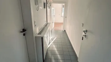 Heller Flur mit Fliesenboden und natürlichem Lichteinfall, der zu weiteren Räumen führt.