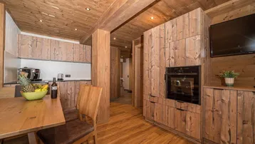Gemütlicher Wohn- und Essbereich mit Holzböden, Holzdecken und integrierter Küche.