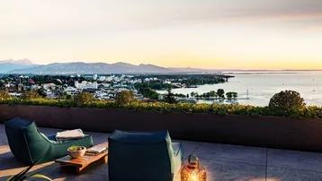 Weitläufige Terrasse mit bequemen Lounge-Möbeln und einem atemberaubenden Blick über die Stadt, den See und die Berge.