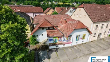 Luftaufnahme eines Gebäudekomplexes mit roten Ziegeldächern und umliegender grüner Landschaft.