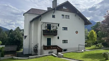 Seitenansicht des Gebäudes mit einem kleinen Balkon und Blick auf die Berge.