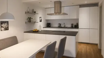Moderne Küche mit Kochinsel, integriertem Essbereich und Holzboden, hell und funktional.