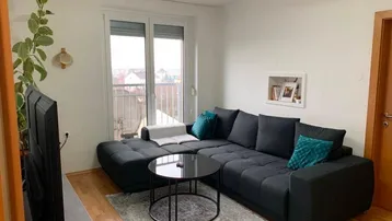 Helles Wohnzimmer mit großem Ecksofa, Couchtisch und Zugang zum Balkon.