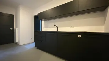 Moderne Küche mit schwarzen Schränken und Arbeitsplatte, bereit für die Installation von Geräten.