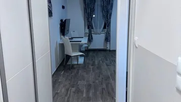 Langer, schmaler Flur mit Holzoptikboden, der zu einem Arbeitsbereich führt.