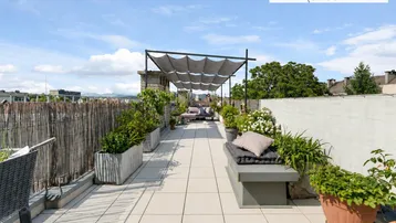 Geräumige Dachterrasse mit Sitzgelegenheiten, Pflanzen und Sonnenschutz, ideal zum Entspannen.