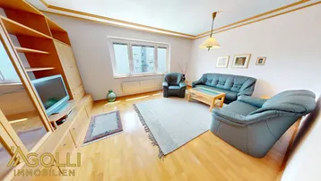 Gemütliches Wohnzimmer mit Holzmöbeln, bequemen Sofas und Blick nach draußen.