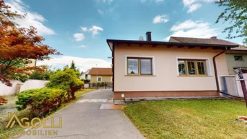 Seitenansicht des Hauses mit Zufahrt und gepflegtem Rasenbereich.