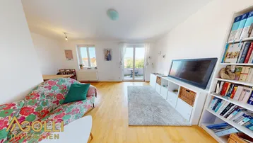 Helles Wohn- und Esszimmer mit Holzboden, Sofa und Zugang zum Balkon.