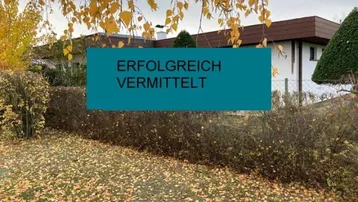 Herbstliche Außenansicht eines Hauses mit braunem Dach und Garten, bedeckt mit gelben Blättern.