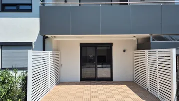 Große, gepflasterte Terrasse mit Sichtschutzwänden und Zugang zum Gebäude.