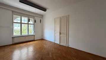 Helles Zimmer mit Fischgrätparkettboden, hohen Decken und großen Fenstern.