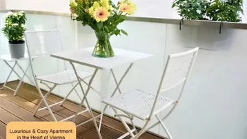 Gemütlicher Balkon mit Holzboden, kleinem Tisch und Stühlen, ideal für entspannte Stunden im Freien.