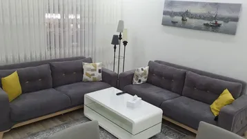 Gemütliches Wohnzimmer mit zwei grauen Sofas, einem weißen Couchtisch und einem Gemälde an der Wand.