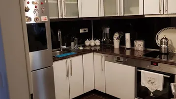 Moderne Küche mit weißen Schränken, dunklen Arbeitsplatten und integrierten Edelstahlgeräten.