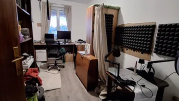 Funktional eingerichtetes Arbeitszimmer mit Schreibtischen, Regalen und Schallschutzplatten an der Wand.