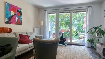 Helles Wohnzimmer mit Zugang zur Terrasse und Blick in den grünen Garten.