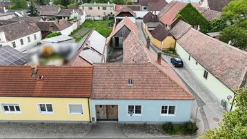 Vogelperspektive eines Wohnhauses mit Ziegeldach, angrenzenden Gebäuden und Gärten.