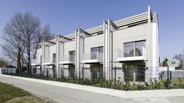 Moderne Reihenhäuser mit Holzfassade und Balkonen unter blauem Himmel.