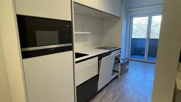 Moderne Küchenzeile mit integrierten Geräten und Zugang zu einem kleinen Balkon, hell und funktional.