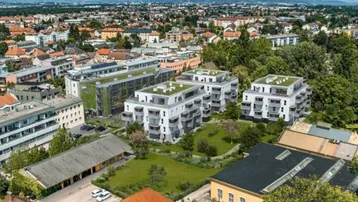 Luftaufnahme eines modernen Wohnkomplexes mit begrünten Dächern und umliegenden Grünflächen in einer städtischen Umgebung.