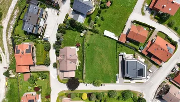 Luftaufnahme eines Wohngebiets mit Häusern, Straßen und einem großen grünen Grundstück in der Mitte.