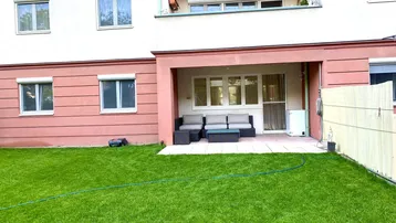 Überdachte Terrasse mit Gartenmöbeln und direktem Zugang zum grünen Rasenbereich.