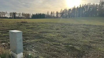 Weitläufiges Grundstück mit Blick auf Wald und Felder unter einem sonnigen Himmel.