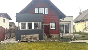 Rückansicht des Hauses mit Rasenfläche, Ziegeldach und einem modernen Anbau.