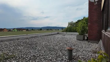 Flachdach mit Kiesbelag und weitem Blick über Felder und die umliegende Landschaft.