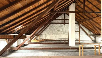 Geräumiger Dachboden mit freiliegenden Holzbalken und Ziegelwänden, bereit für den Ausbau.