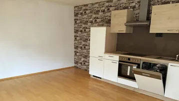 Moderne Einbauküche mit hellen Fronten, integrierten Geräten und Laminatboden.