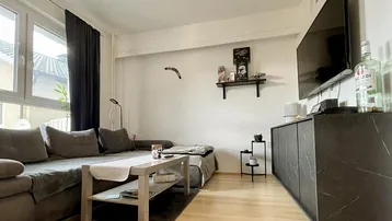 Helles Wohnzimmer mit großem Ecksofa, Holzboden und modernem TV-Möbel mit Flachbildschirm.