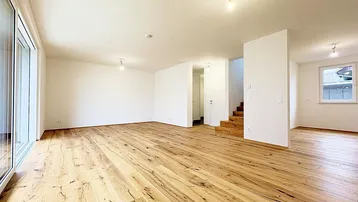 Geräumiges, helles Wohnzimmer mit neuem Holzboden und Zugang zu einem Fenster mit Blick nach draußen.