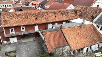 Luftaufnahme des Anwesens mit roten Ziegeldächern und Innenhof, umgeben von weiteren Gebäuden.